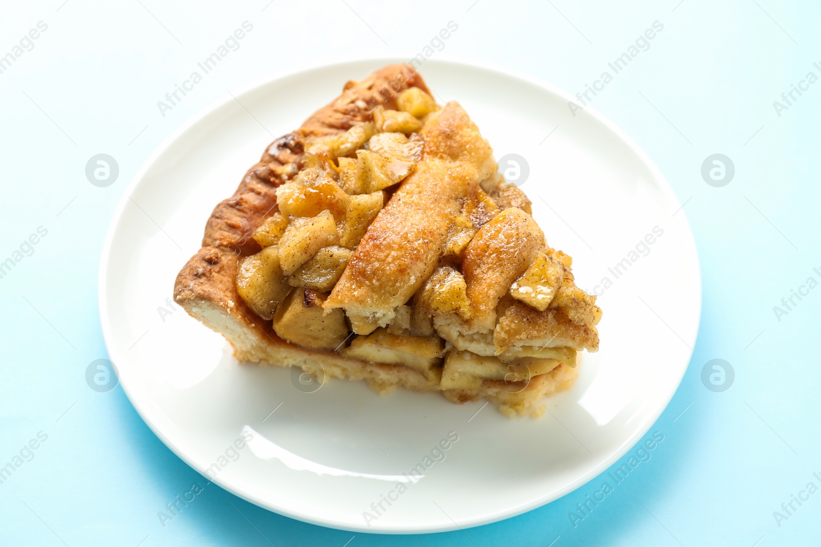 Photo of Slice of homemade apple pie on light blue background, closeup