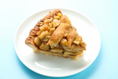 Photo of Slice of homemade apple pie on light blue background, closeup