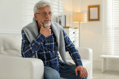 Photo of Lonely senior man sitting on sofa at home. Space for text