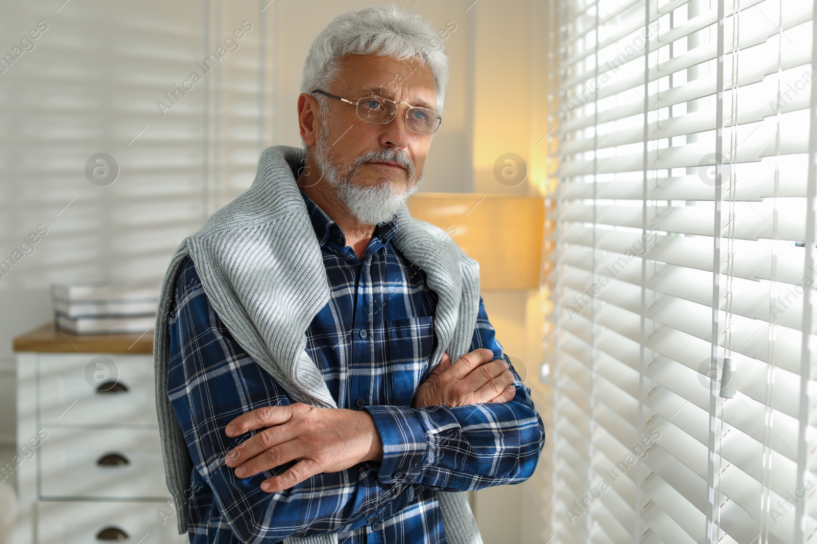 Photo of Lonely senior man looking out window indoors