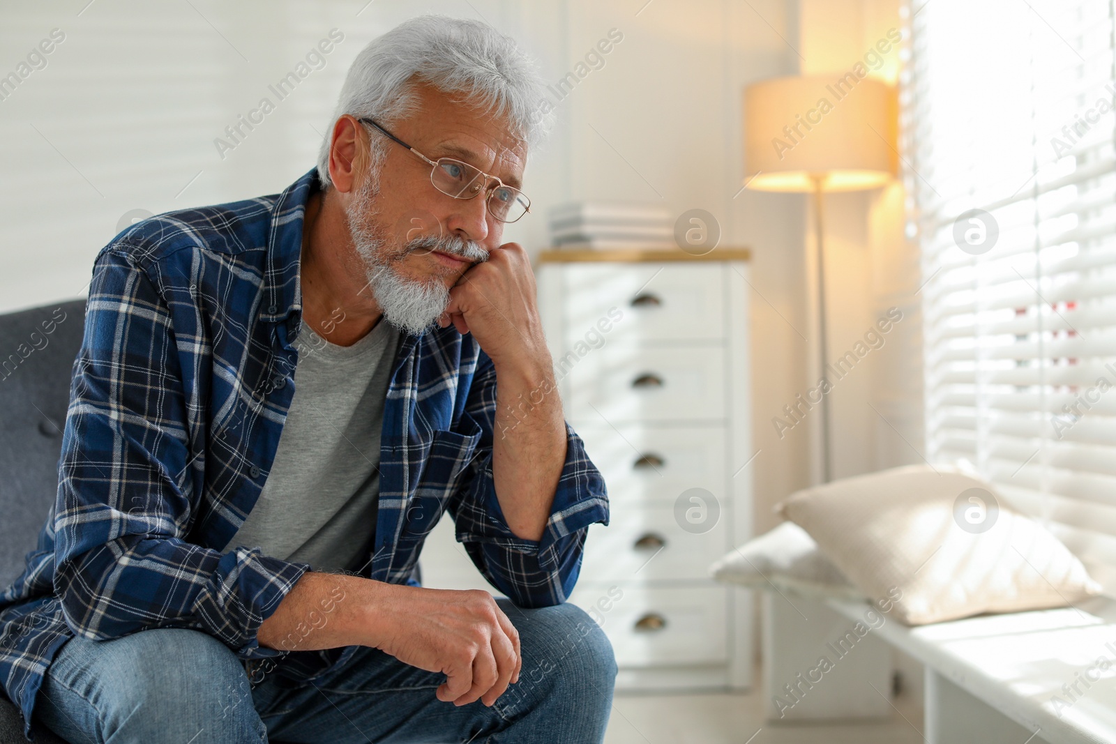 Photo of Lonely senior man sitting in armchair at home. Space for text