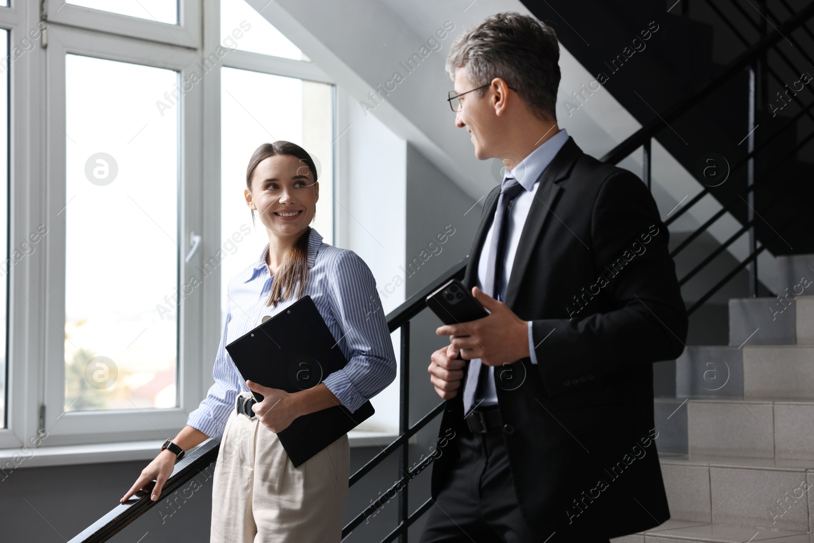 Photo of Coworkers talking while going down stairs in office