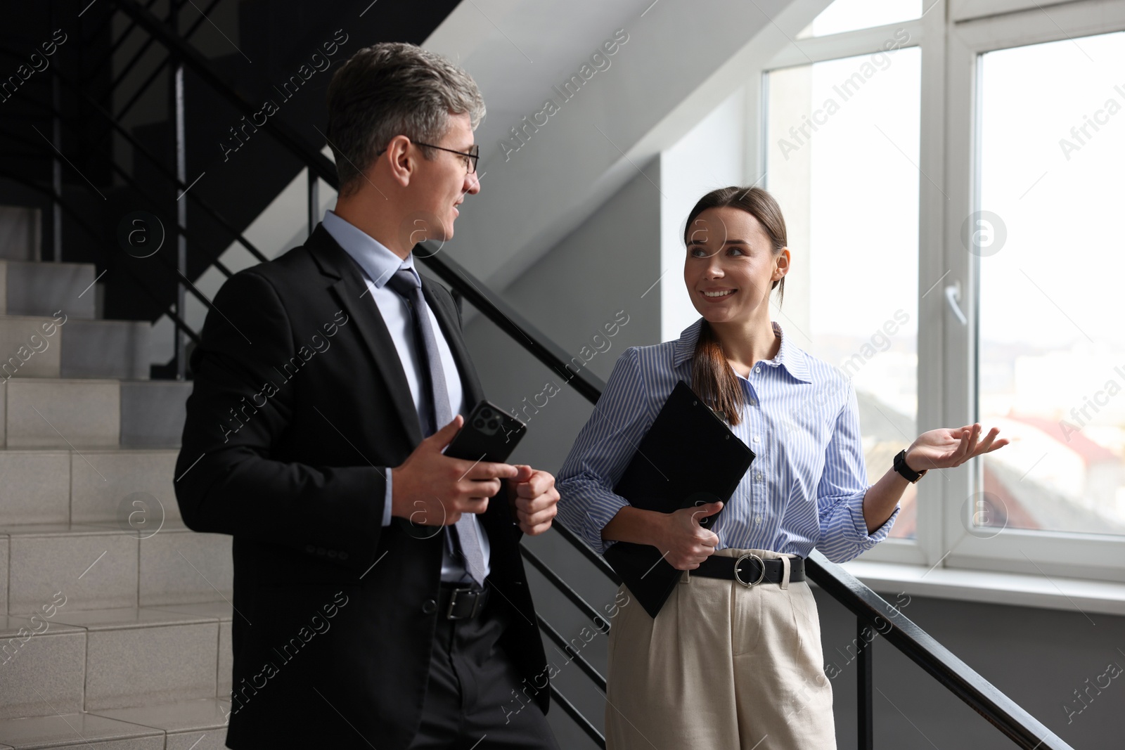 Photo of Coworkers talking while going down stairs in office