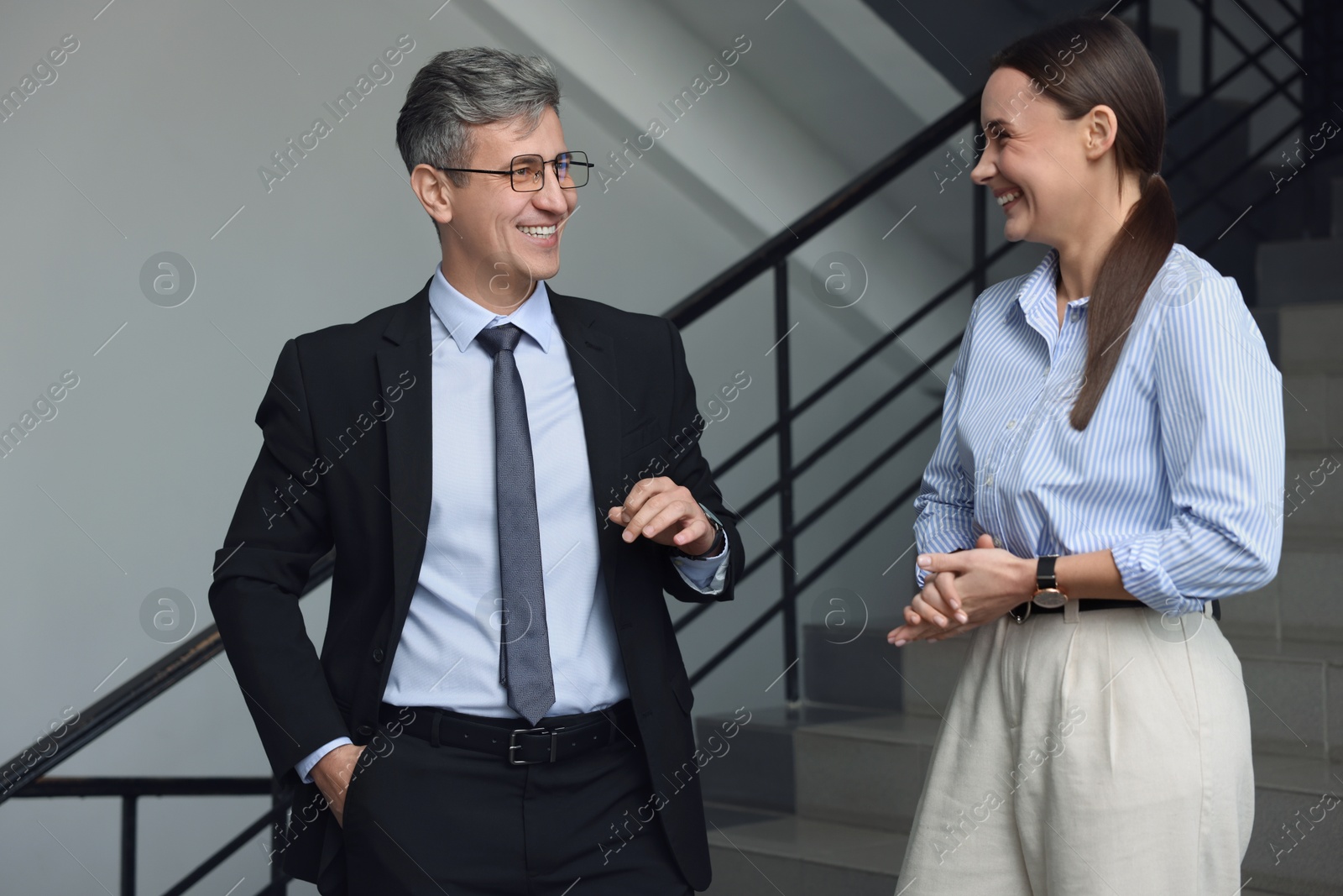 Photo of Coworkers talking while going down stairs in office