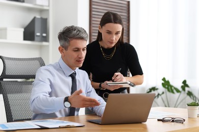 Photo of Coworkers working together at table in office