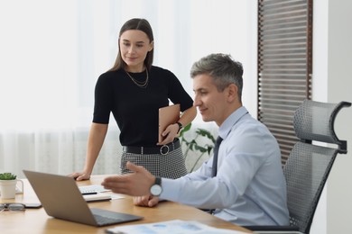 Photo of Coworkers working together at table in office