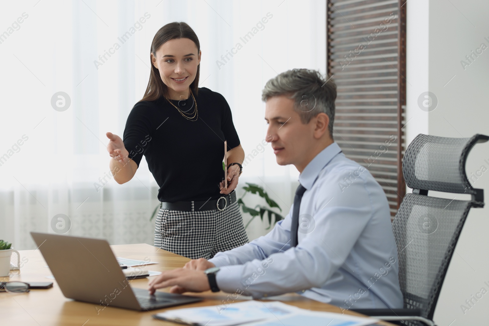 Photo of Coworkers working together at table in office