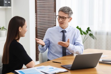 Photo of Coworkers working together at table in office