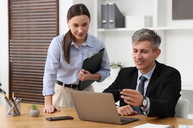 Photo of Coworkers with laptop working together in office