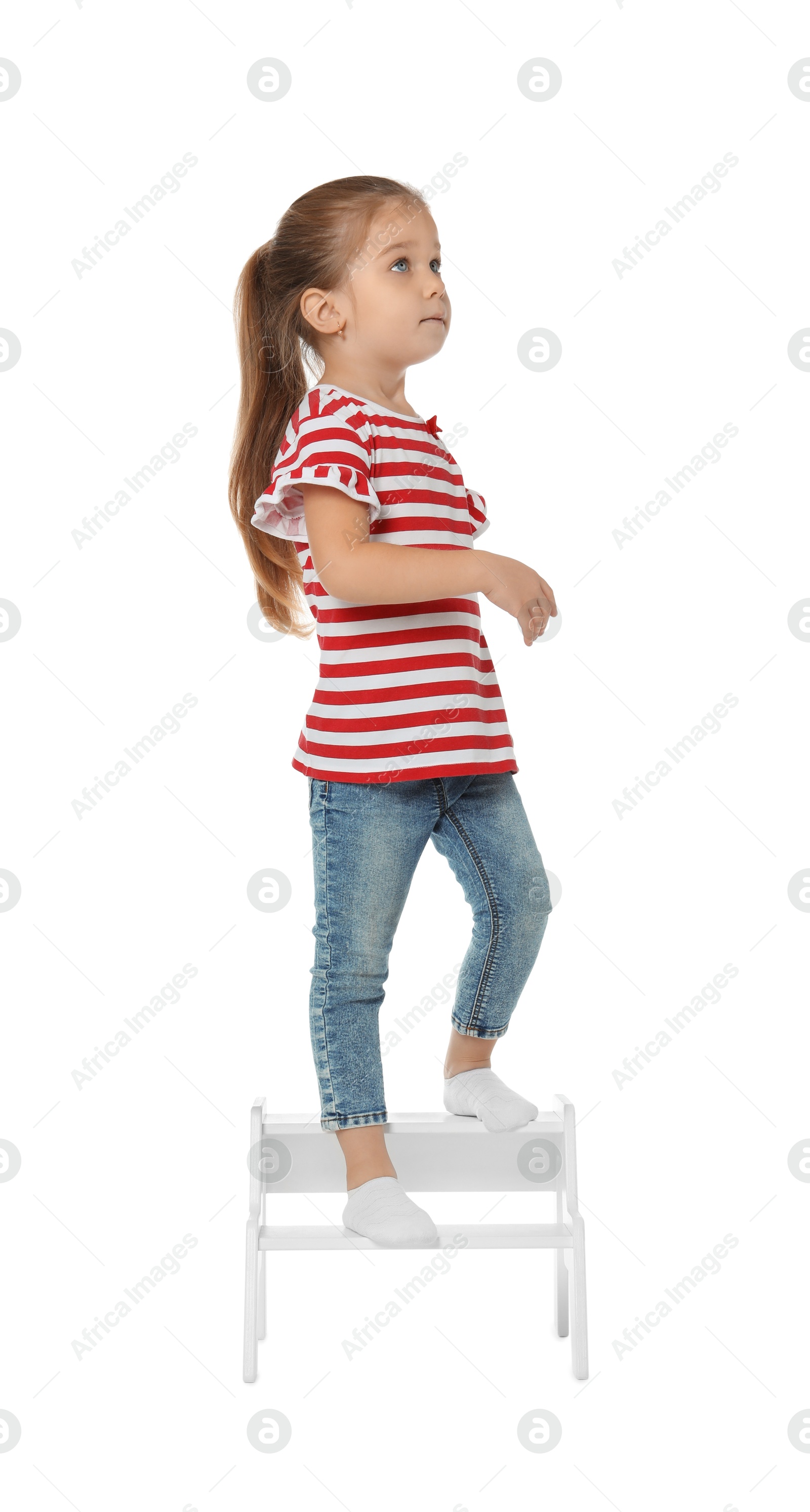 Photo of Little girl standing on step stool against white background