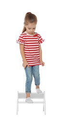 Photo of Little girl standing on step stool against white background