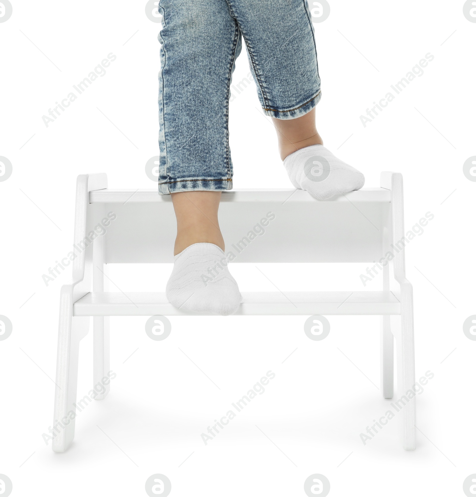 Photo of Little girl standing on step stool against white background, closeup