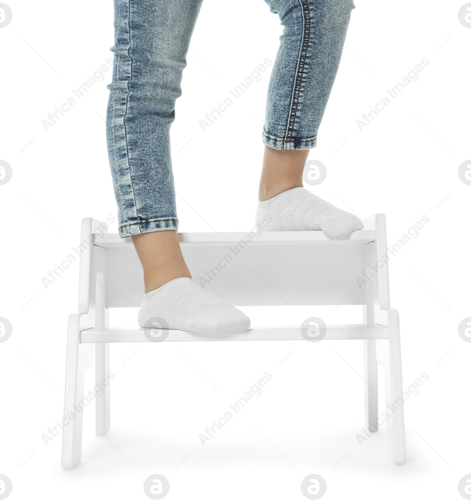 Photo of Little girl standing on step stool against white background, closeup