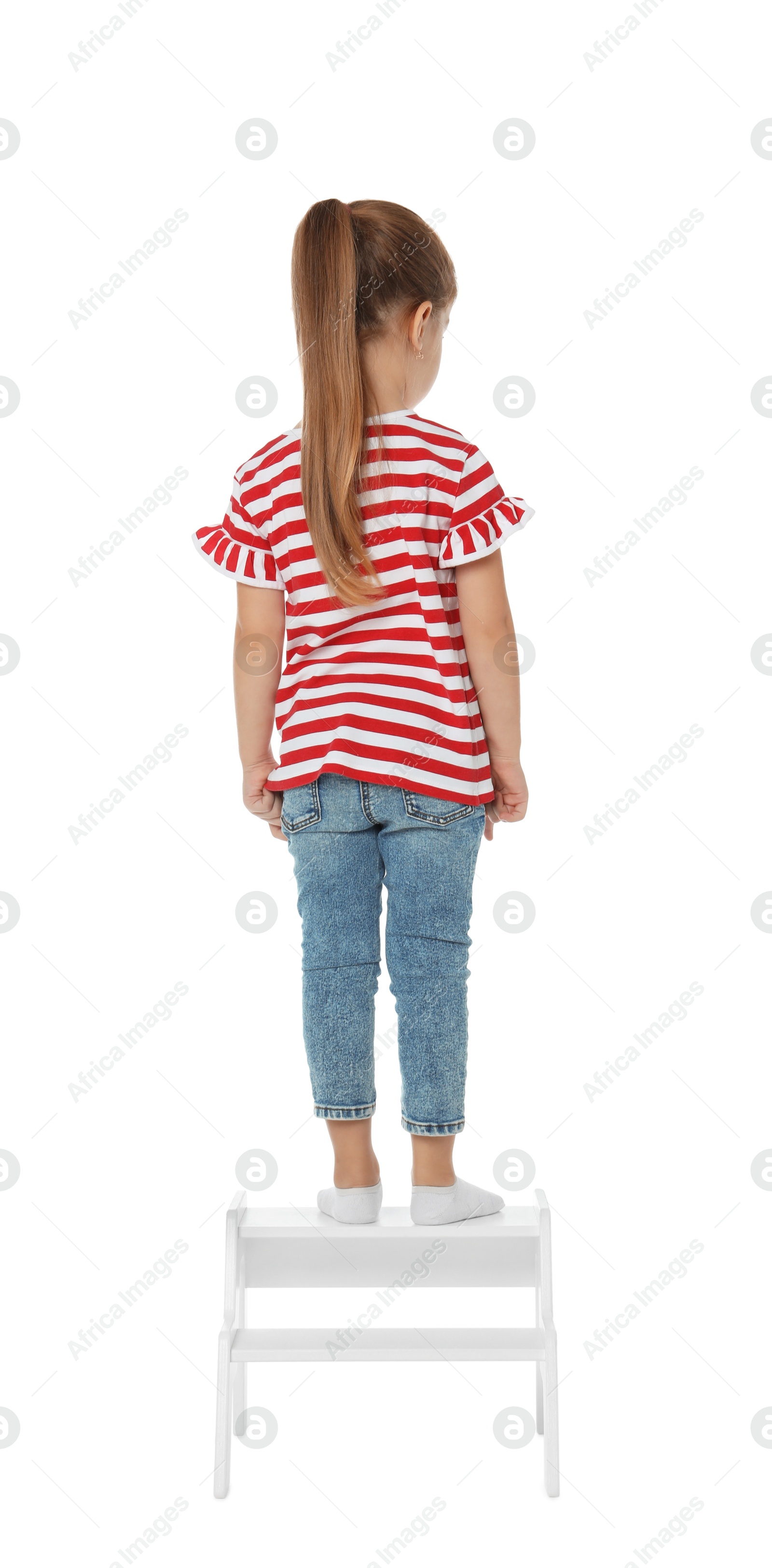 Photo of Little girl standing on step stool against white background, back view