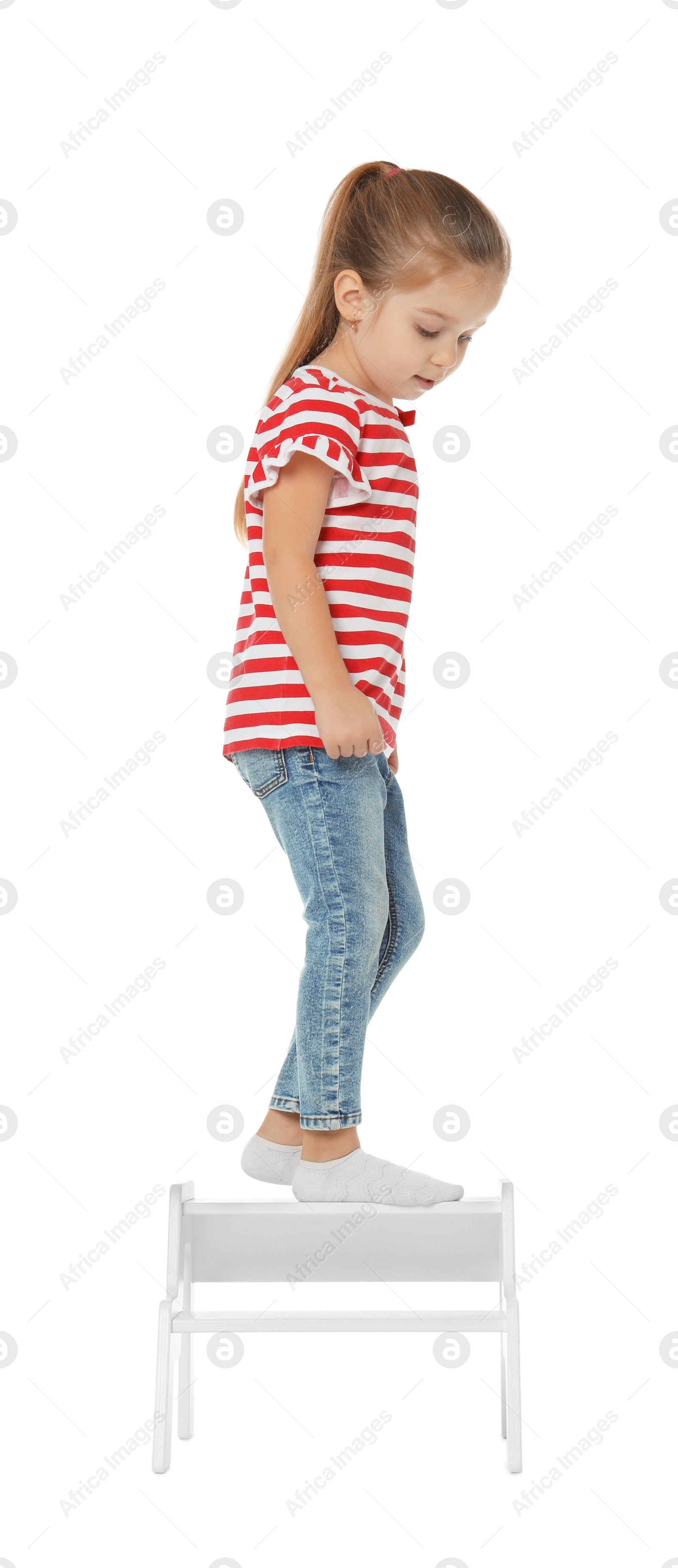 Photo of Little girl standing on step stool against white background