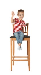 Little girl sitting on stool against white background