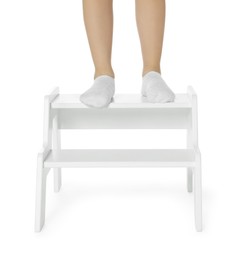 Photo of Little girl standing on step stool against white background, closeup