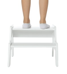 Photo of Little girl standing on step stool against white background, closeup