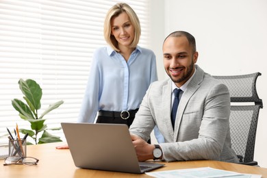 Coworkers with laptop working together in office