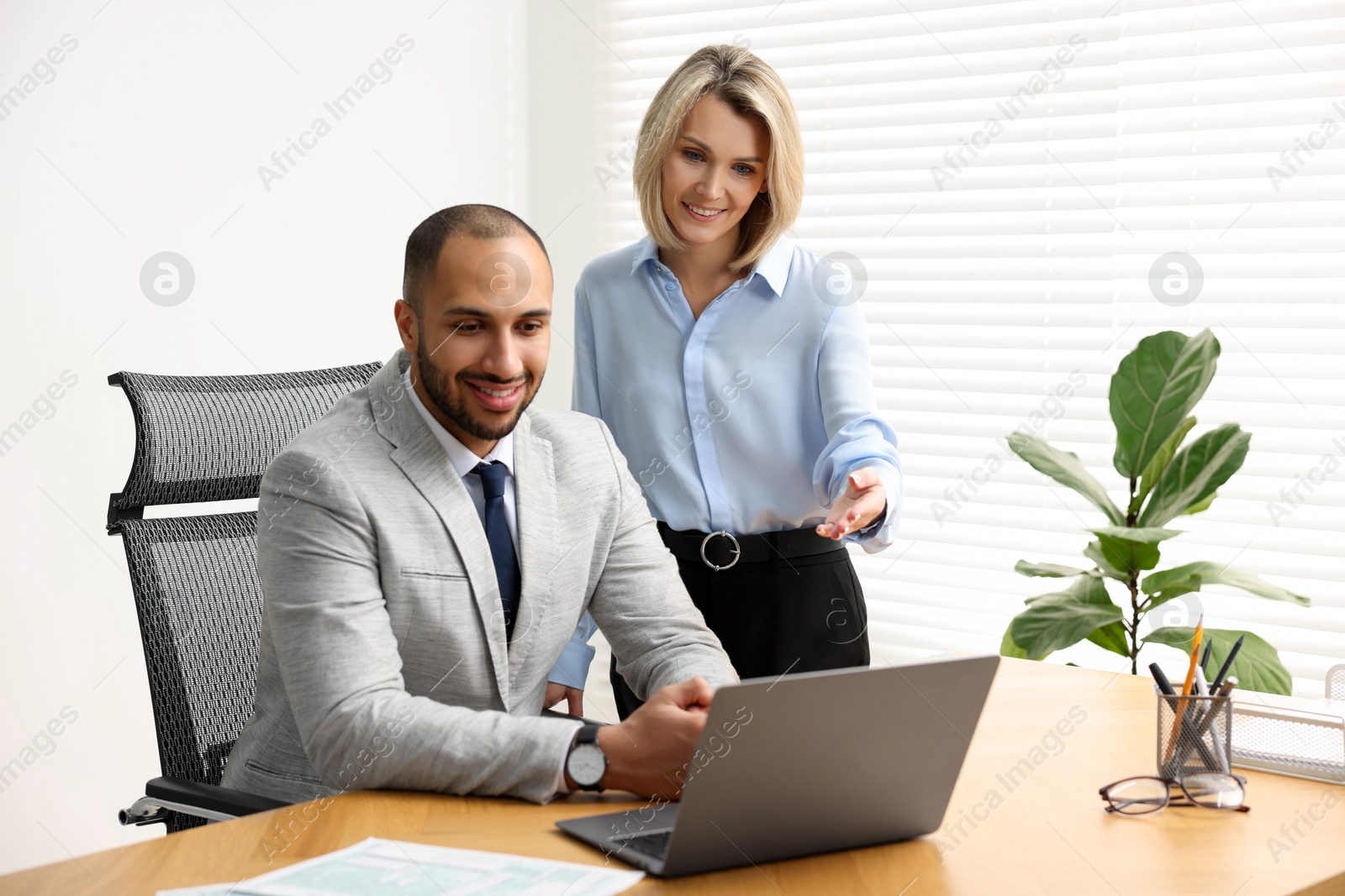 Photo of Coworkers with laptop working together in office