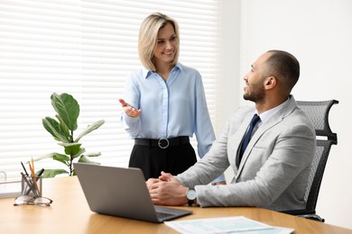 Coworkers with laptop working together in office