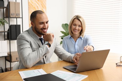 Photo of Coworkers with laptop working together in office