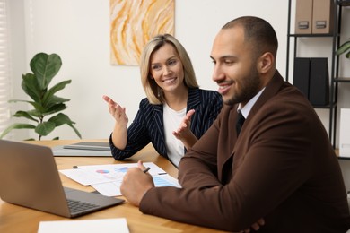 Coworkers with laptop working together in office