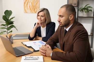 Coworkers with laptop working together in office