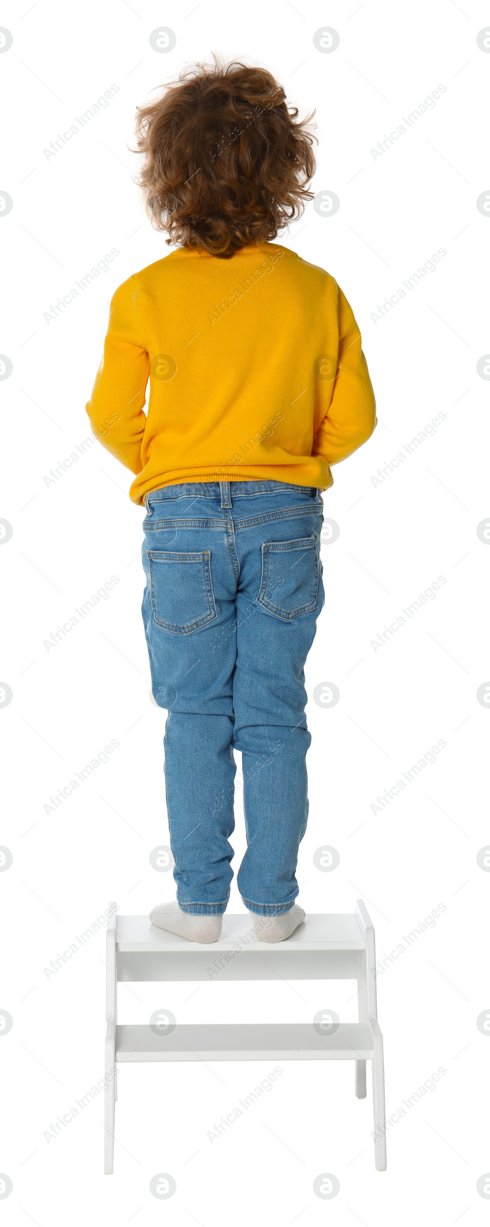 Photo of Little boy standing on step stool against white background, back view