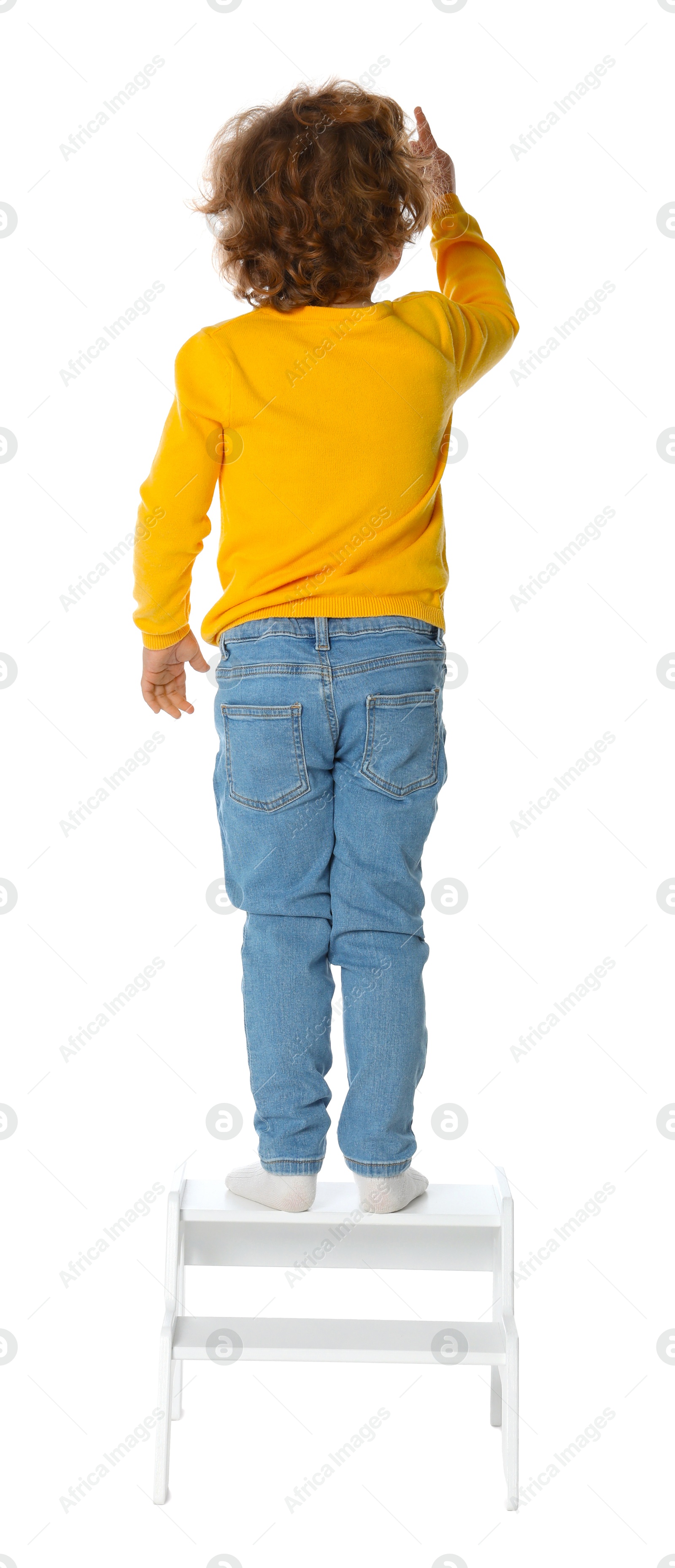 Photo of Little boy standing on step stool against white background, back view