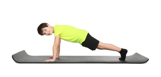 Photo of Boy exercising on fitness mat against white background. Sport activity