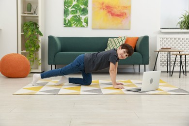 Photo of Boy having training with online coach via laptop at home