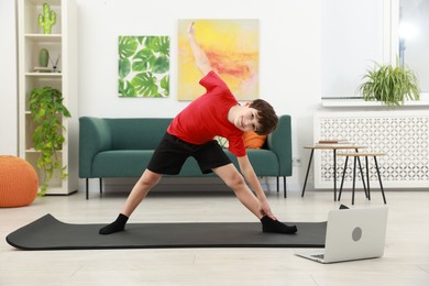 Photo of Boy having training with online coach via laptop at home