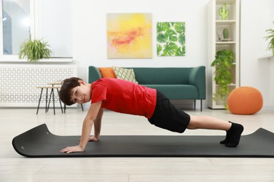 Photo of Boy doing exercise on fitness mat at home. Sport activity