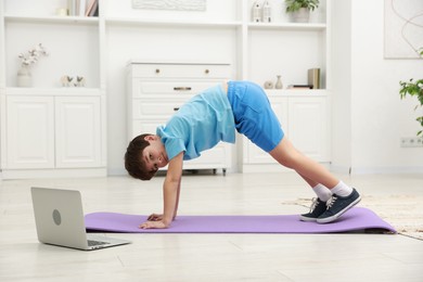 Boy having training with online coach via laptop at home