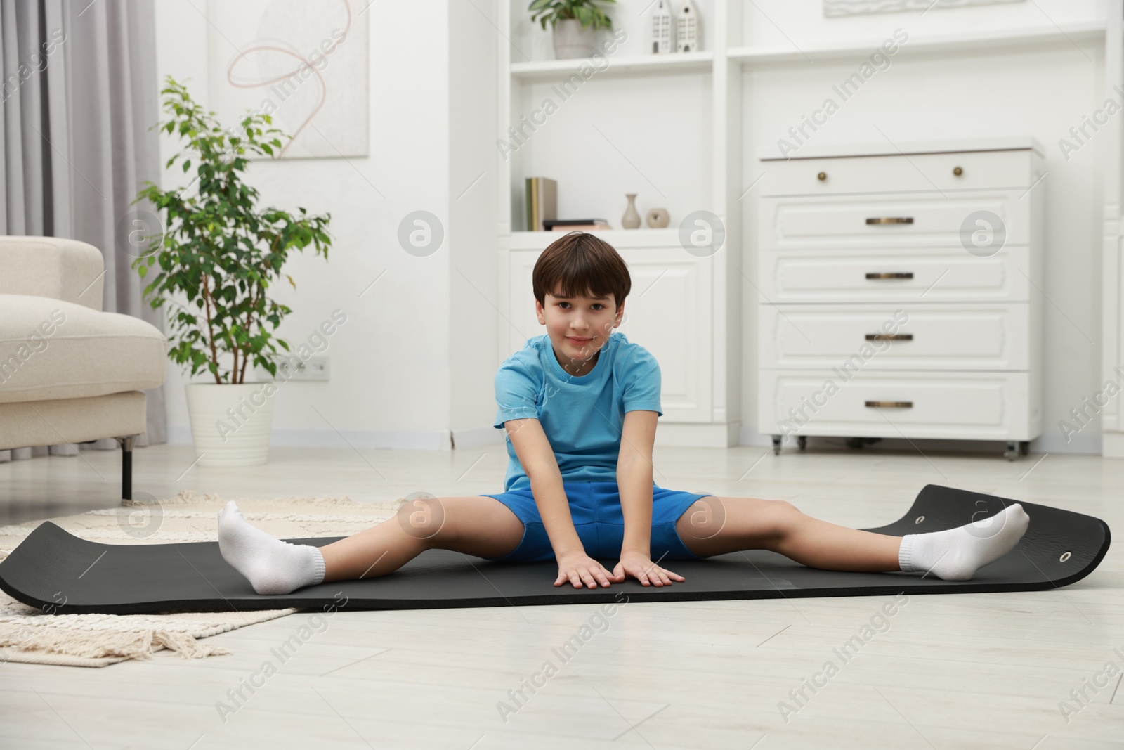 Photo of Boy doing exercise on fitness mat at home. Sport activity