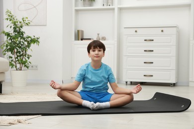 Photo of Boy doing exercise on fitness mat at home. Sport activity