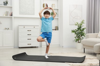 Photo of Boy doing exercise on fitness mat at home. Sport activity