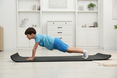 Photo of Boy doing exercise on fitness mat at home. Sport activity