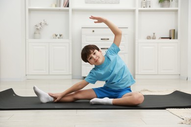 Photo of Boy doing exercise on fitness mat at home. Sport activity