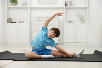 Photo of Boy doing exercise on fitness mat at home. Sport activity