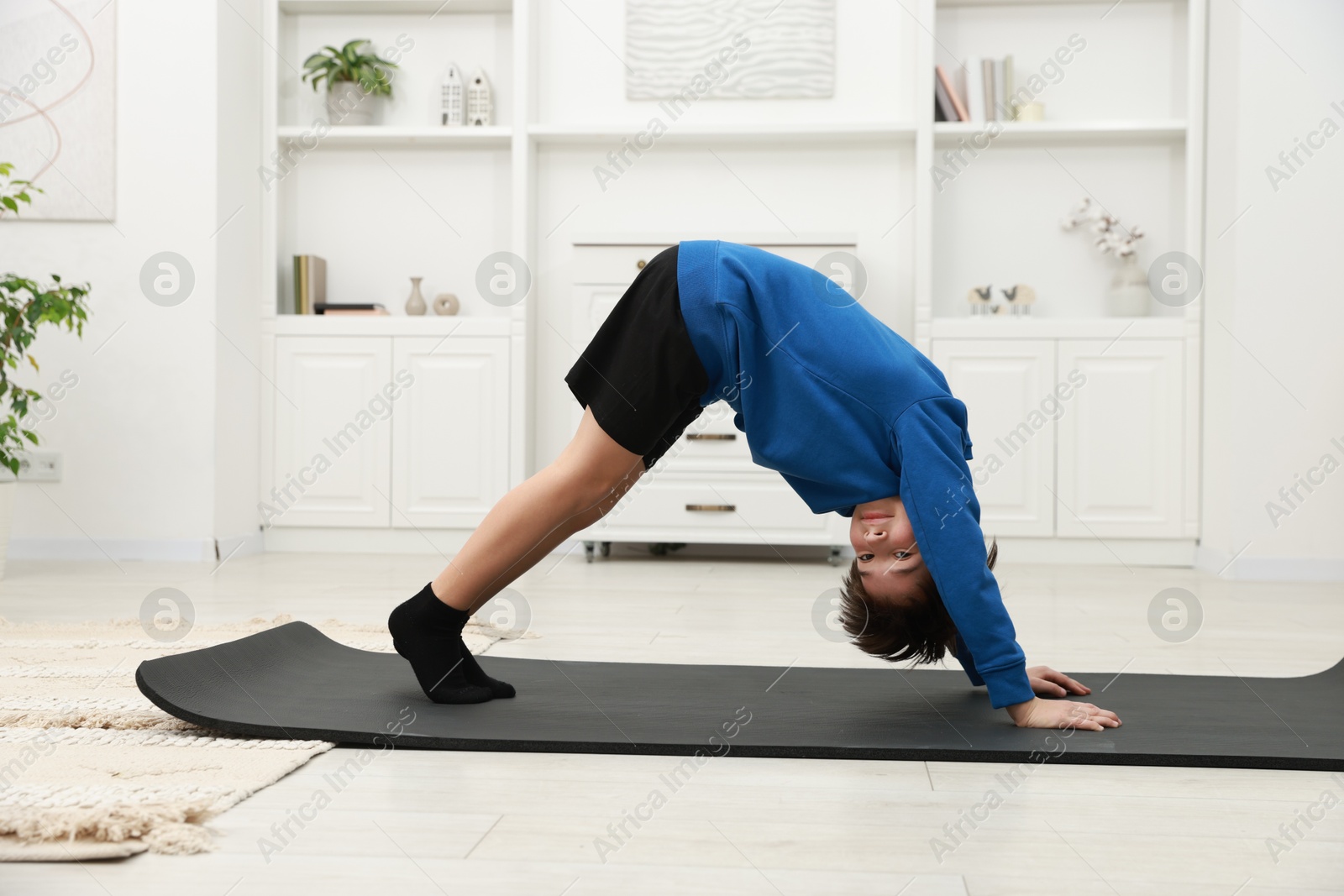 Photo of Boy doing exercise on fitness mat at home. Sport activity