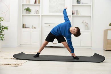 Photo of Boy doing exercise on fitness mat at home. Sport activity