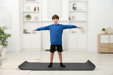 Photo of Boy doing exercise on fitness mat at home. Sport activity