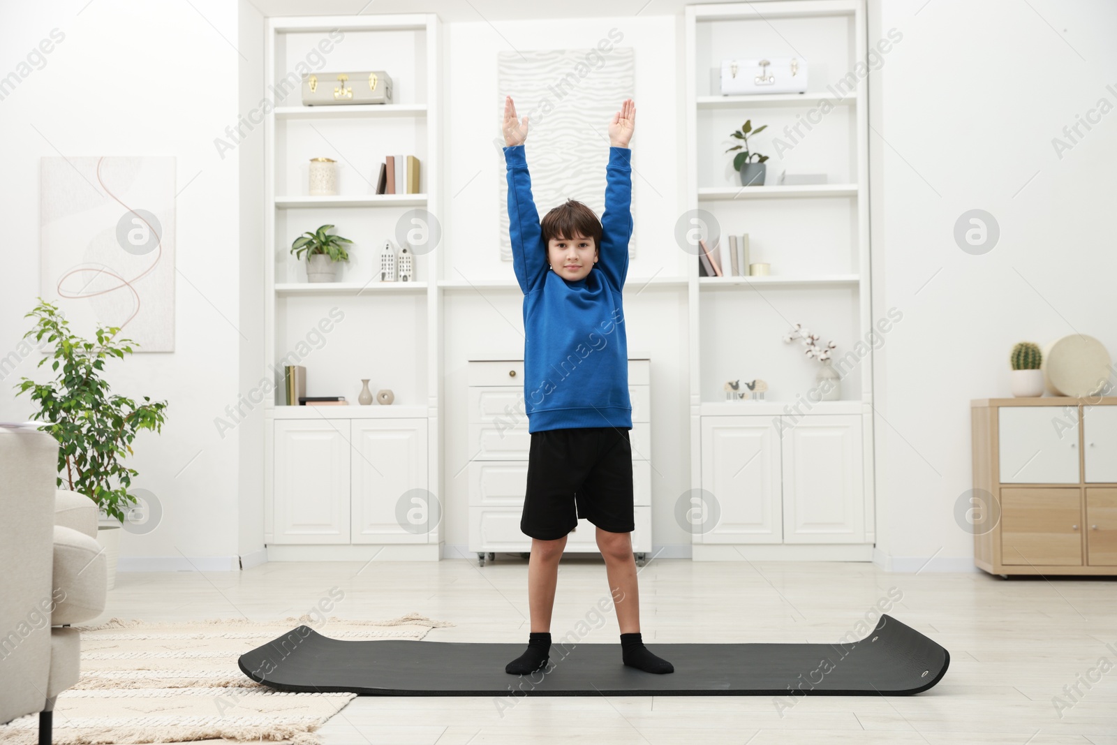 Photo of Boy doing exercise on fitness mat at home. Sport activity