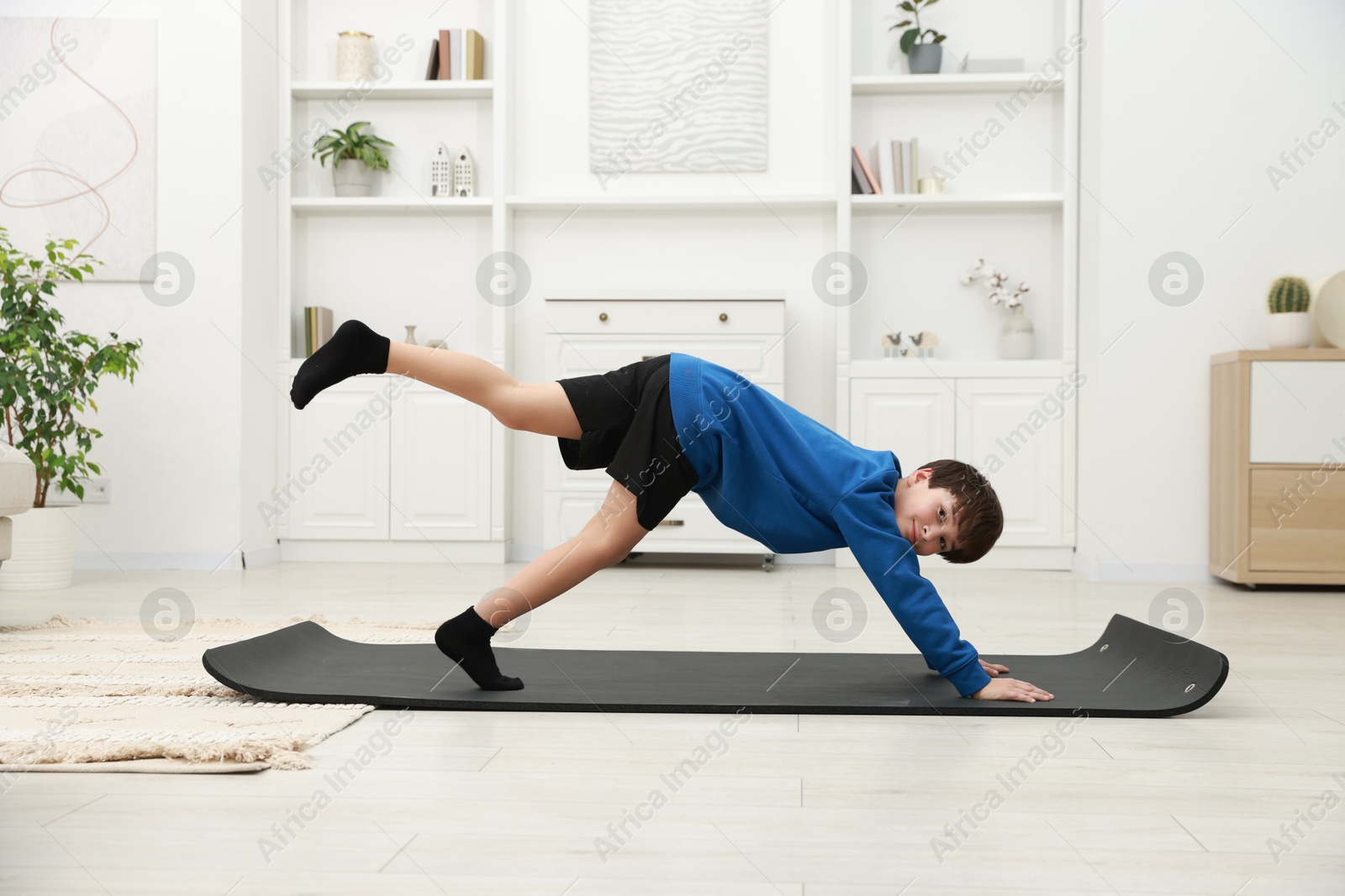 Photo of Boy doing exercise on fitness mat at home. Sport activity