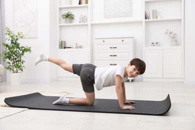 Photo of Boy doing exercise on fitness mat at home. Sport activity