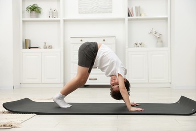 Photo of Boy doing exercise on fitness mat at home. Sport activity