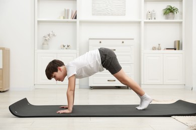 Photo of Boy doing exercise on fitness mat at home. Sport activity