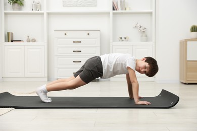 Photo of Boy doing exercise on fitness mat at home. Sport activity